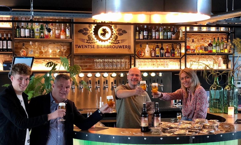 Proosten op Twentse bierkoek Vier mensen proosten in de Twentse Bierbrouwerij op de nieuwe Twentse Bierkoek